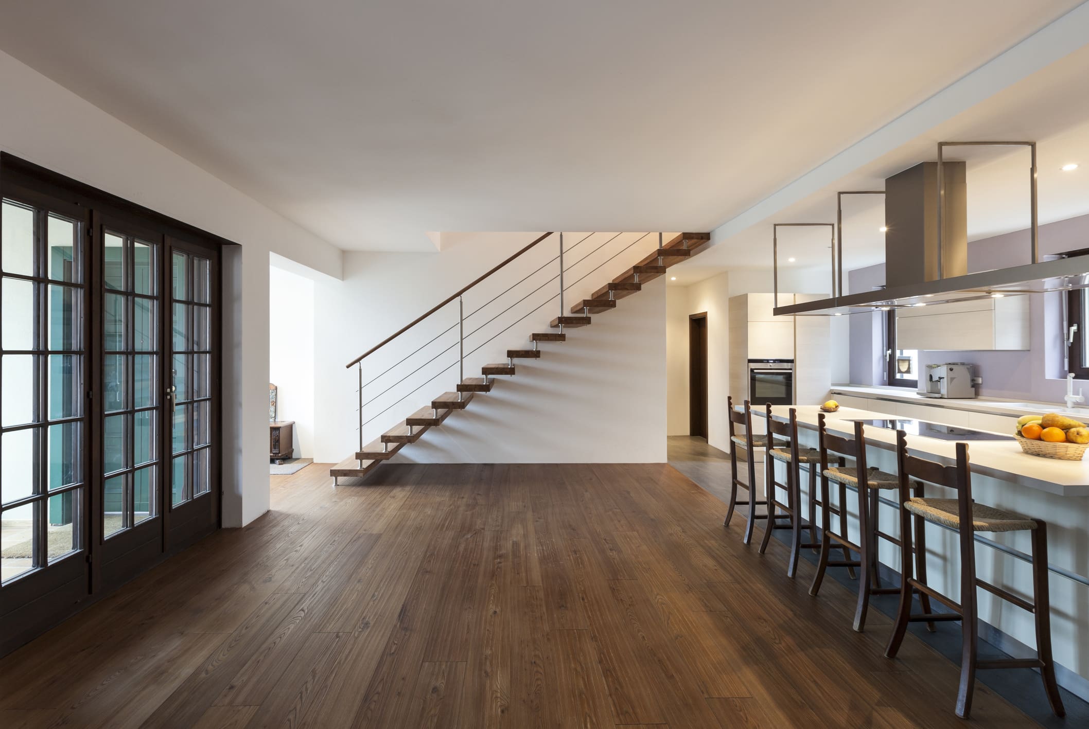 Modern kitchen and staircase with wooden flooring.